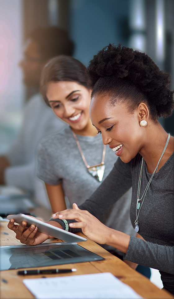 Dos mujeres sonriendo y mirando un iPad